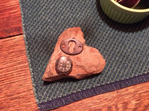 Rock in shape of heart with compass and metal trinket on it